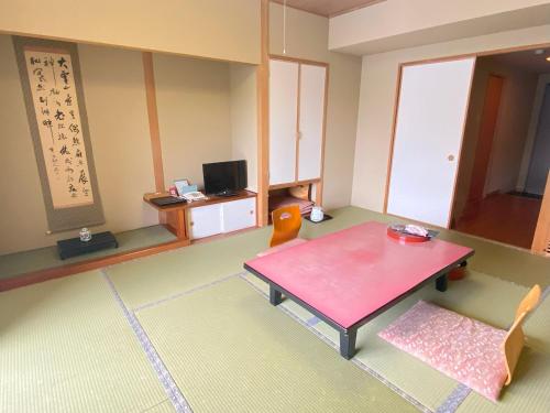 a living room with a red table and chairs at Shikaribetsu Kohan Onsen Hotel Fusui in Shikaoi
