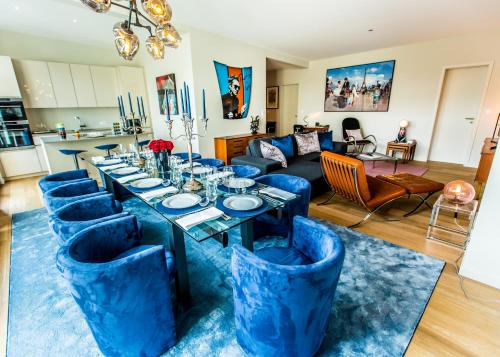 uma sala de estar com uma mesa longa e cadeiras azuis em Magnifique Penthouse 3 chambres et terrasse sur l'Avenue Louise em Bruxelas
