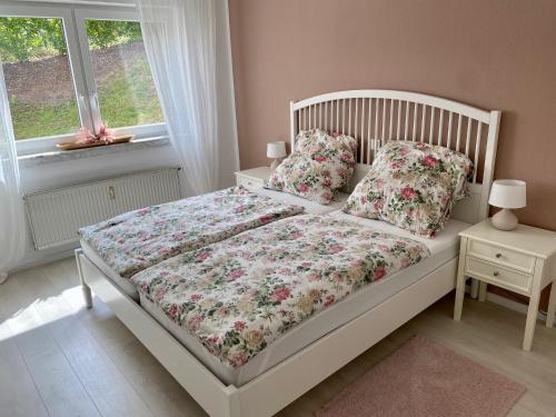 a bedroom with a white bed with flowers on it at NEU: Ferienwohnung Zum Nussbaum - Landhausstil & Moseltalblick in Traben-Trarbach