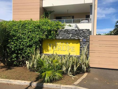 un panneau jaune sur un mur en pierre devant une maison dans l'établissement Appartement TERUPE, à Papeete