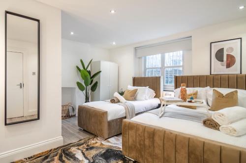 2 camas en una habitación con espejo en Livestay-Funky Trendy Modern 3 Bed 3 Bath House In Dalston en Londres