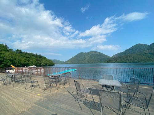 a group of chairs and tables on a deck next to a lake at Shikaribetsu Kohan Onsen Hotel Fusui in Shikaoi
