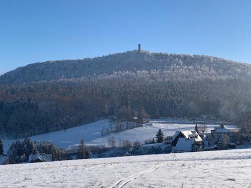 a snow covered hill with a house and a mountain at Chalupa Krompach in Krompach