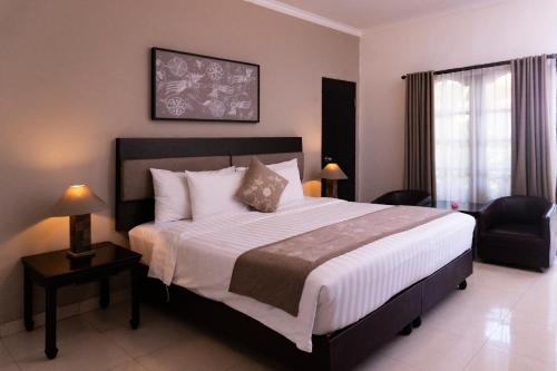 um quarto com uma cama grande e uma cadeira em Sarinande Hotel em Seminyak