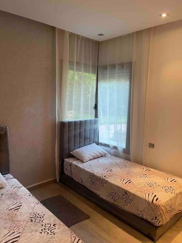 a bedroom with two beds and a window at Superbe appartement à mohammadia in Mohammedia