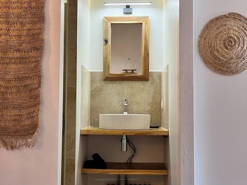 a bathroom with a sink and a mirror on a wall at Ti Kaloo, 2ème ligne, 40 m du Lagon in Saint-Leu
