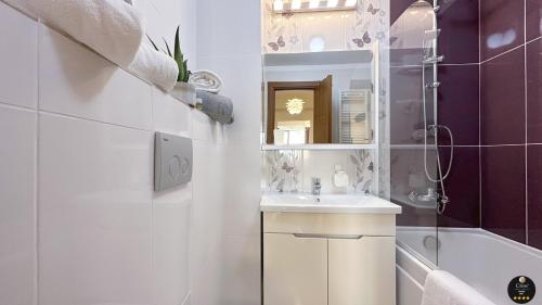 a bathroom with a sink and a mirror and a tub at Deluxe Criss Solid Residence Mamaia in Mamaia