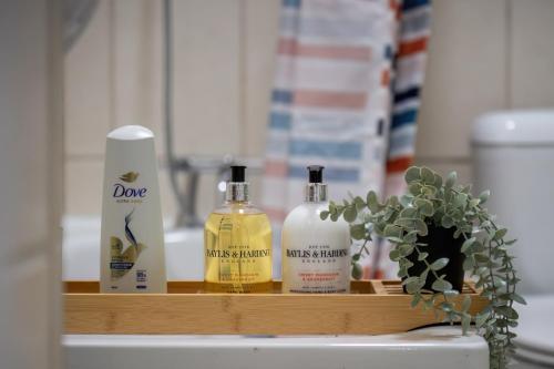 a shelf with three bottles of soap and a plant at Livestay-Funky Trendy Modern 3 Bed 3 Bath House In Dalston in London