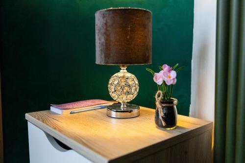 a lamp on a table with books and a vase of flowers at Find yourself apartment Dunkerque in Coudekerque-Branche