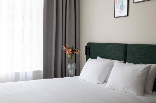 a bedroom with a white bed with a vase of flowers at Bob W Oosterpark in Amsterdam