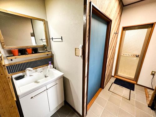 a bathroom with a sink and a mirror at Cosmo St Inn Noboribetsu 3min walk from JR Noboribetsu st in Tomiura