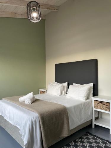sypialnia z dużym łóżkiem z białą pościelą i poduszkami w obiekcie The Cabin w mieście Swakopmund