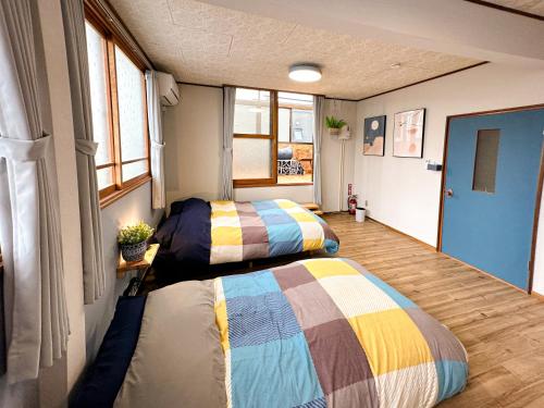 two beds in a small room with windows at Cosmo St Inn Noboribetsu 3min walk from JR Noboribetsu st in Noboribetsu