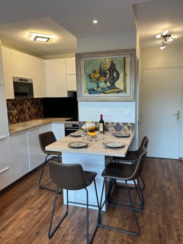 une cuisine avec une table et des chaises ainsi qu'une peinture murale. dans l'établissement F2 rénové, à Saint-Lary-Soulan