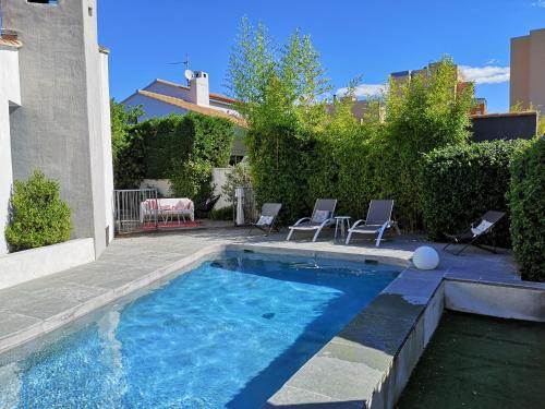 a swimming pool with chairs and a table in a yard at VILLA MONTPELLIER in Montpellier