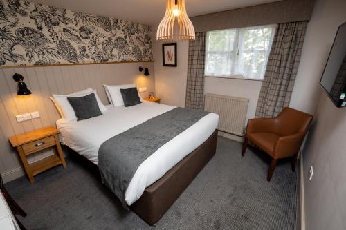 - une chambre avec un grand lit et une chaise dans l'établissement Cedars Inn by Greene King Inns, à Barnstaple