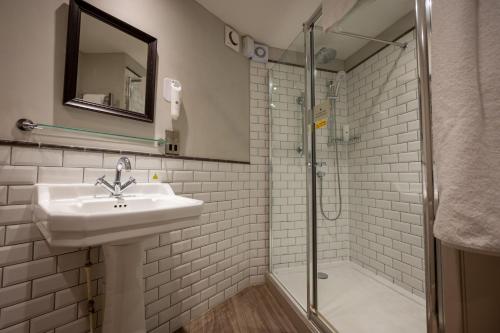 La salle de bains est pourvue d'un lavabo et d'une douche. dans l'établissement Cedars Inn by Greene King Inns, à Barnstaple