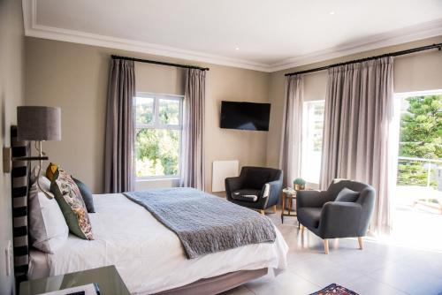 a bedroom with a bed and two chairs at The Whale on Main B&B in Hermanus