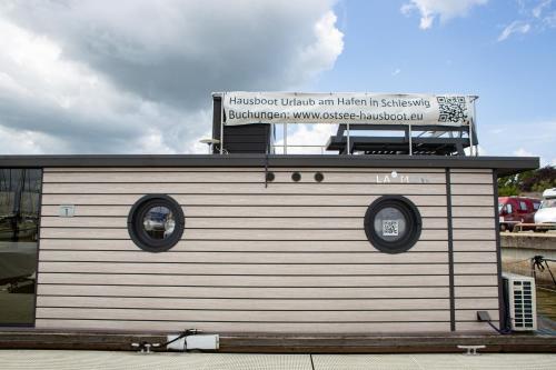 a small building with a sign on top of it at Ostsee Hausboot Schleswig Ostseeblick 1 in Schleswig