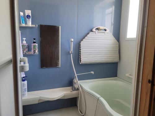 uma casa de banho azul com uma banheira e um lavatório em 하루카오후나에 민숙 em Tsushima