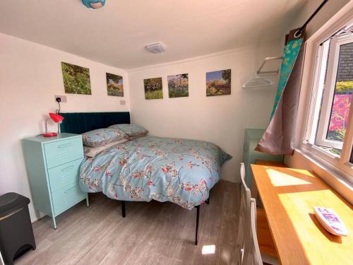 a bedroom with a bed and a dresser and a window at Guest house Truro garden retreat in Kenwyn
