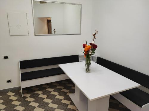 a white table with a vase of flowers on it at Stella Polare Sensorial Home in Lido di Ostia