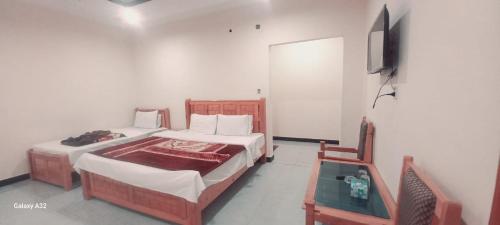 a bedroom with two beds and a tv and a table at Galiyat Inn Hotel, Balakot by LMC in Bālākot