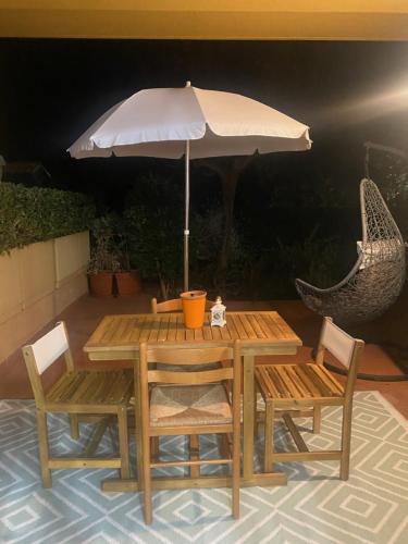 a wooden table with two chairs and an umbrella at Appartamento con piscina e idromassaggio a 5 min dal mare in Santa Veneranda