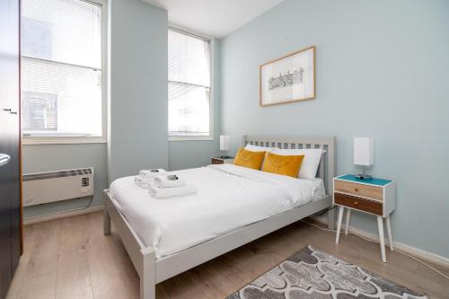 una camera da letto con un grande letto bianco con cuscini arancioni di Stunning Central 2BR Flat btw Soho & Covent Garden a Londra