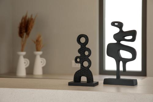 two black sculptures sitting on a table in front of a mirror at Anapollo Boutique Hotel Adults Only in Naxos Chora