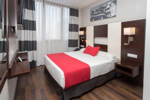 a hotel room with a large bed with a red pillow at Hotel & Spa Villa Olimpica Suites in Barcelona