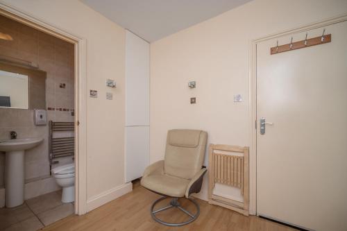 a bathroom with a chair and a sink and a toilet at Flexistay Aparthotel Tooting in London