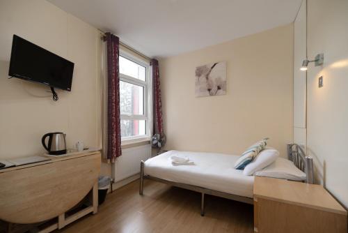 倫敦的住宿－Flexistay Aparthotel Tooting，卧室配有一张床,墙上配有电视。
