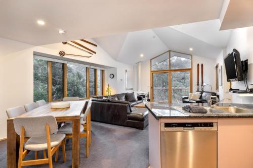 a kitchen and living room with a table and a couch at Lhotsky 4 in Thredbo