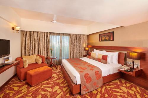 um quarto de hotel com uma cama grande e uma televisão em The Pride Hotel, Nagpur em Nagpur