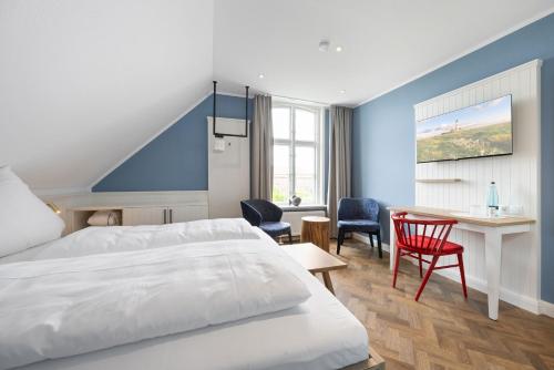 Habitación de hotel con cama, escritorio y sillas en Zum Goldenen Anker en Tönning