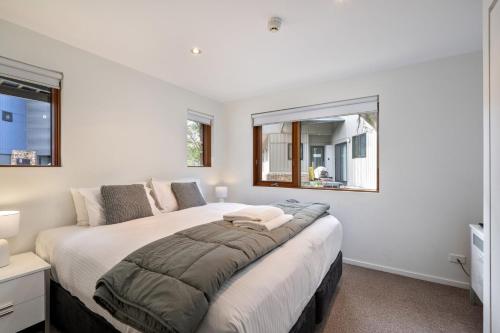 1 dormitorio con 1 cama grande y 2 ventanas en Snow Stream 3 Bedroom and loft with gas fire garage parking and balcony, en Thredbo