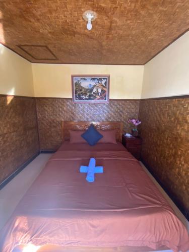 a bed with a blue ribbon on top of it at D'Yoga Bamboo House in Kintamani