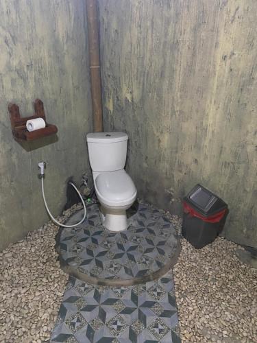 a bathroom with a toilet and a trash can at D'Yoga Bamboo House in Kintamani