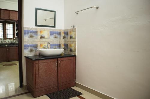 a bathroom with a sink and a mirror on the wall at 4BR AC House near Edappally Lulu Mall & AIMS Kochi in Ernakulam