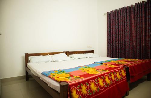 a bed with a colorful blanket on top of it at 4BR AC House near Edappally Lulu Mall & AIMS Kochi in Ernakulam