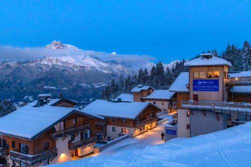 a resort in the snow with a mountain in the background at Goélia Les Chalets des Pistes in Combloux