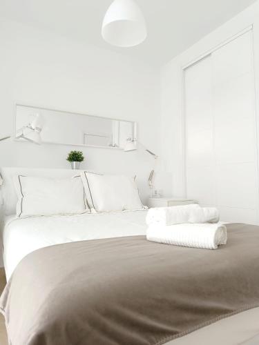 una camera bianca con un grande letto con cuscini bianchi di SHERRY SUITES V Apartamentos PARKING GRATUITO a Jerez de la Frontera