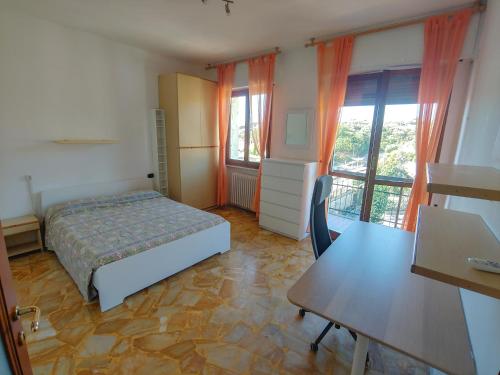 a bedroom with a bed and a desk and windows at Luminoso appartamento vacanze vista mare in centro in Celle Ligure