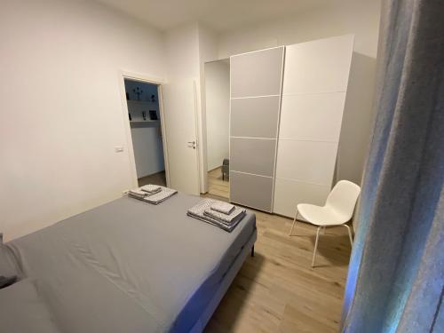 a white bedroom with a bed and a chair at Casettadellafotografia in Senigallia