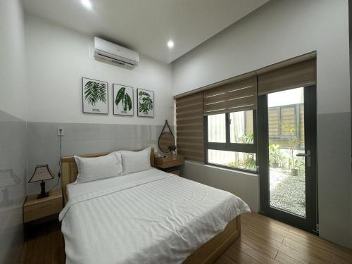 ein Schlafzimmer mit einem weißen Bett und einem Fenster in der Unterkunft OYO 1192 Victory Hotel Dien Ban in Đà Nẵng