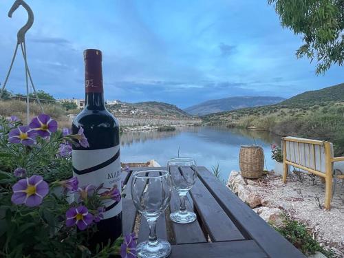 卡薩米里的住宿－Garden Lake Camping，木桌旁的一瓶葡萄酒,带两杯