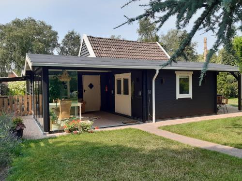 a small black shed with a white door at De Groninger Zeeuw by Droomvilla in Bellingwolde