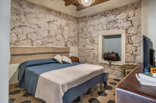 ein Schlafzimmer mit einem Bett und einer Steinmauer in der Unterkunft La Tabarchina - Carloforte Lovely Apt With Terrace! in Carloforte