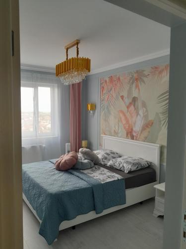 een slaapkamer met een bed en een kroonluchter bij Luxury Home in Oradea